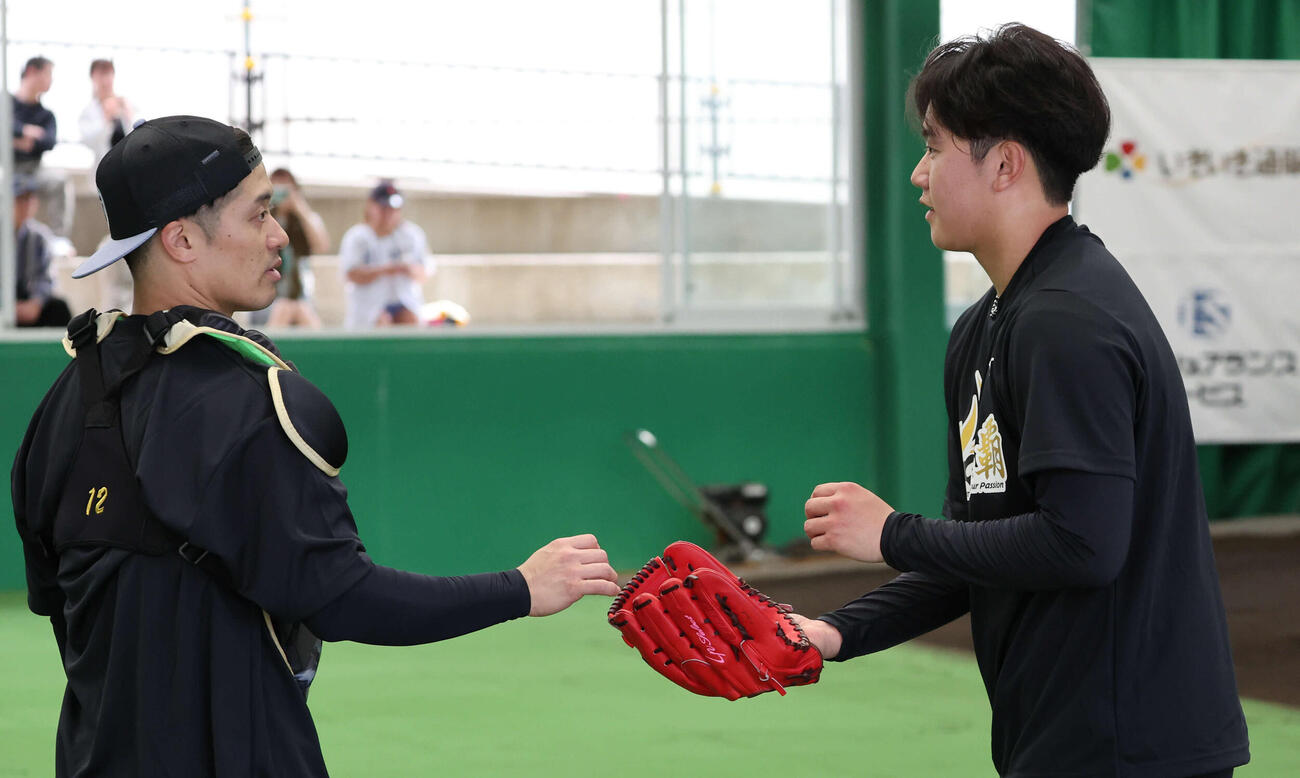 ブルペンで投げ終えた阪神門別（右）は受けた坂本と話す（撮影・西尾就之）