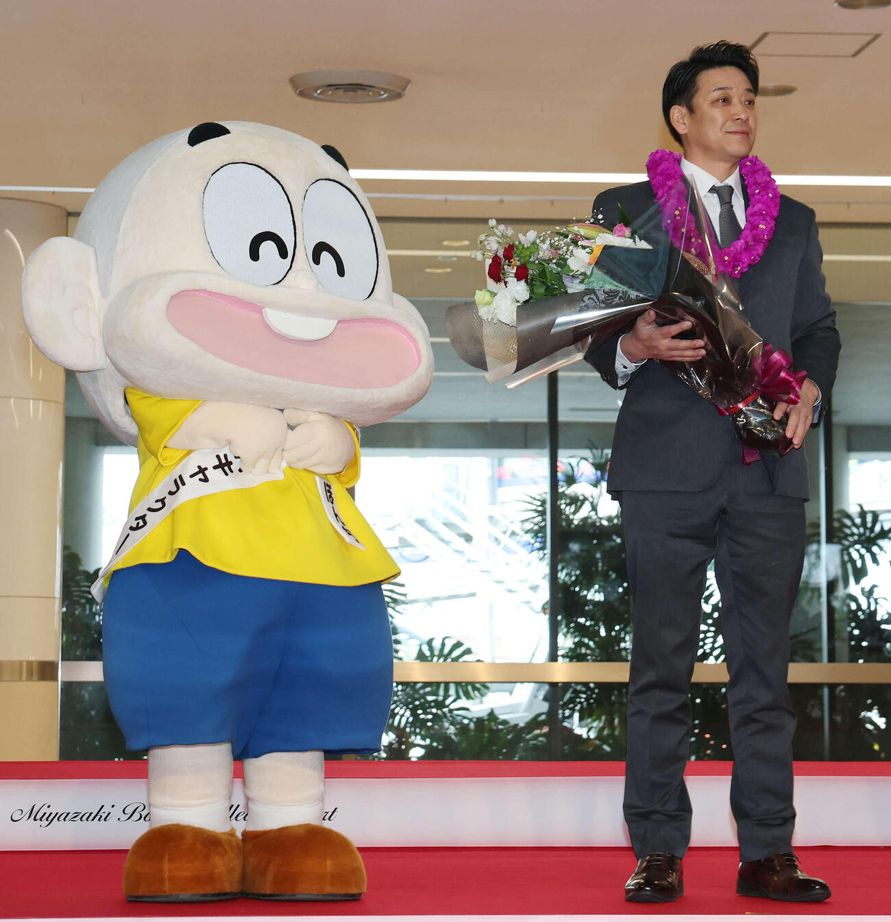 宮崎空港に到着し歓迎セレモニーを受けるロッテのサブロー監督。左は都城市PRキャラクター兼PR本部長のぼんちくん（撮影・宮地輝）