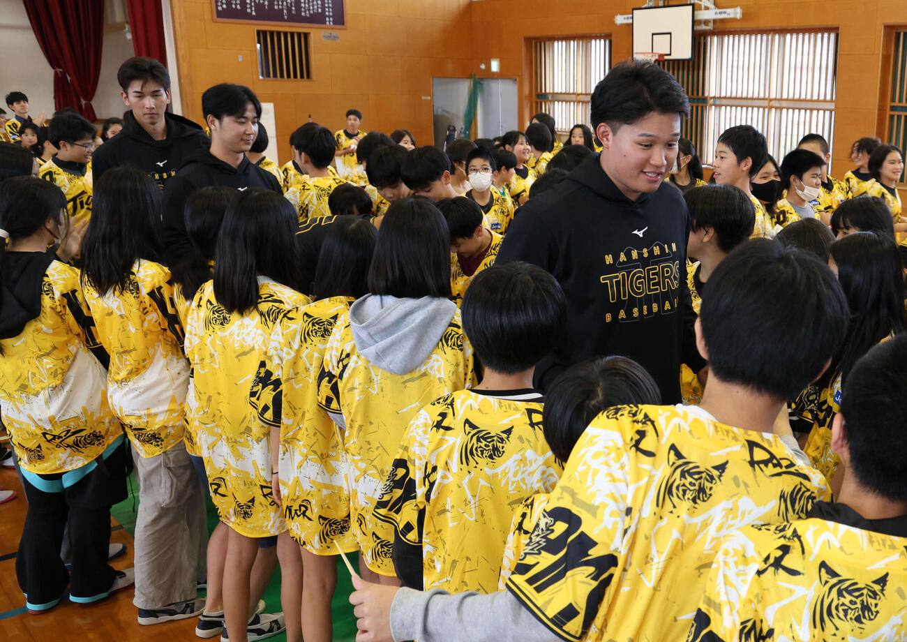 沖縄・うるま市の田場小学校を訪問した阪神森下は生徒たちとタッチをかわしながら会場をあとにする（撮影・西尾就之）