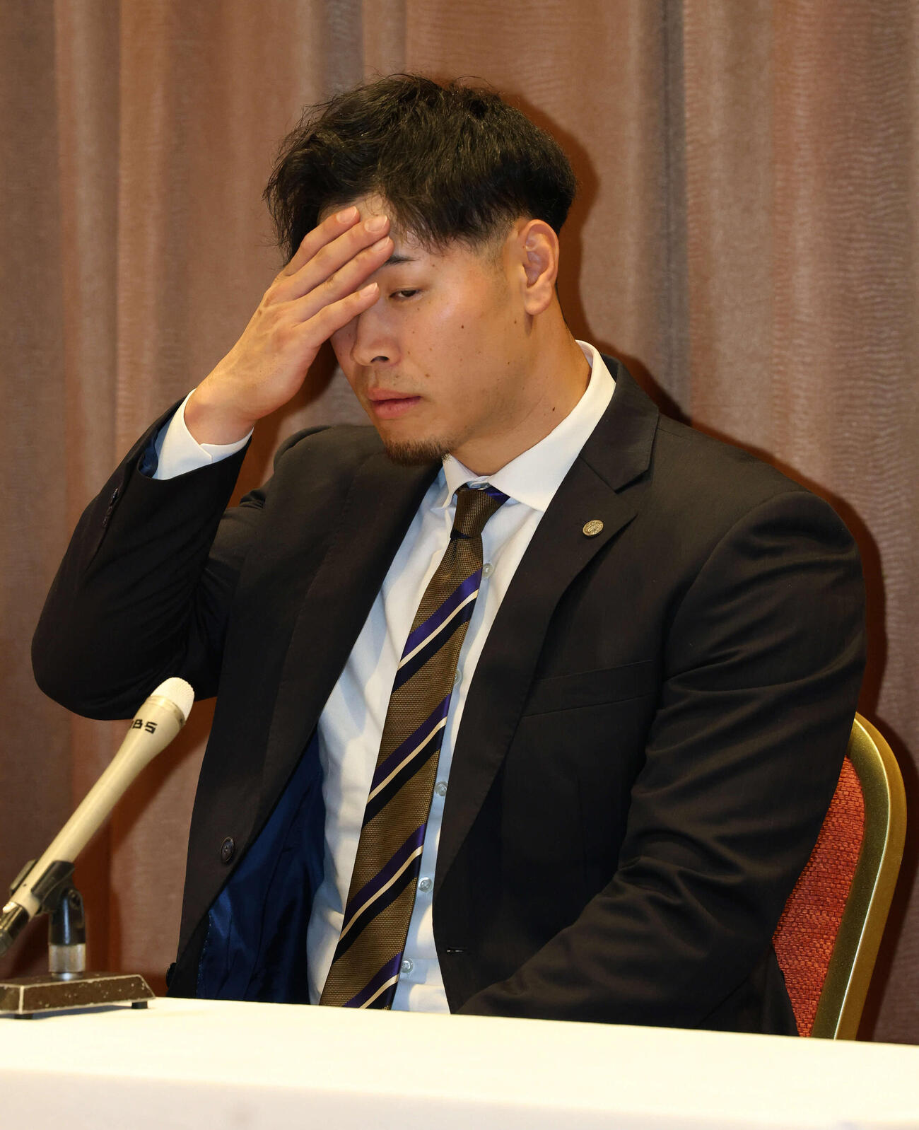 キャンプ宿舎に到着した阪神佐藤輝は契約更改の会見の最中に汗を拭う（撮影・西尾就之）