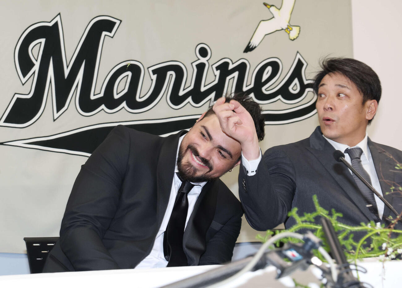入団会見に飛んできた虫を避けるロッテのカスティーヨ。右はサブロー監督（撮影・宮地輝）