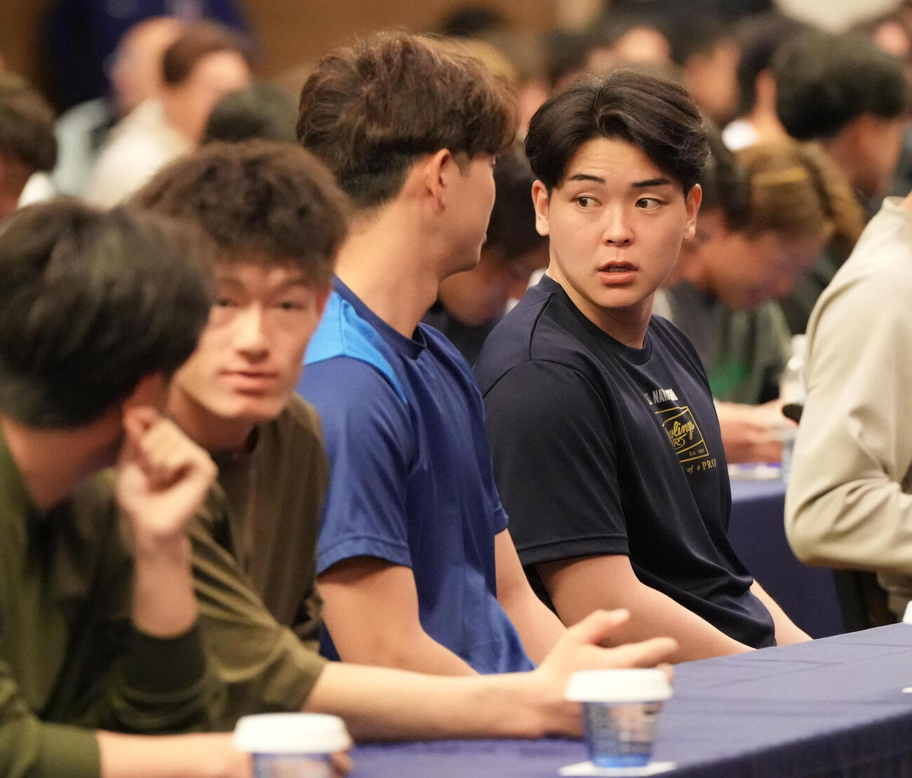 中西（右）は全体ミーティング会場の席に着く（撮影・森本幸一）
