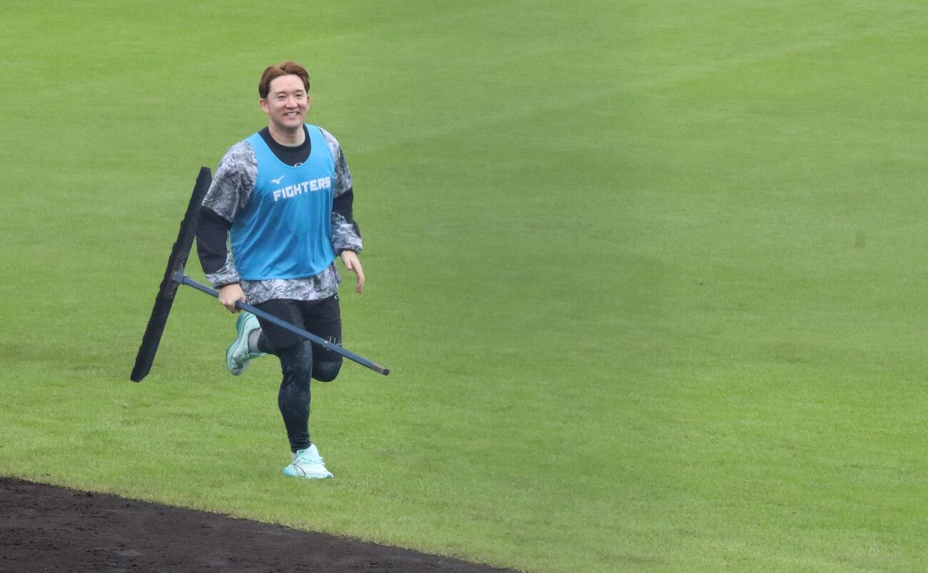 トンボを持ってグラウンドを走る日本ハムOBの杉谷氏（撮影・永野高輔）