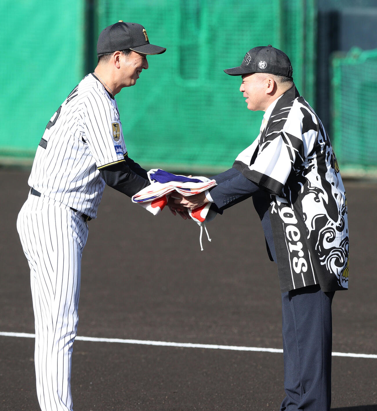 歓迎セレモニーで宜野座村の當真村長（右）にレプリカのチャンピオンフラッグ渡す阪神藤川監督（撮影・上山淳一）