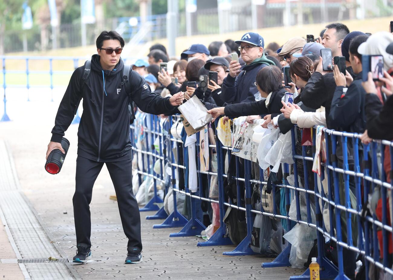 ファンからプレゼントを受け取り球場入りする日本ハム田中（撮影・黒川智章）