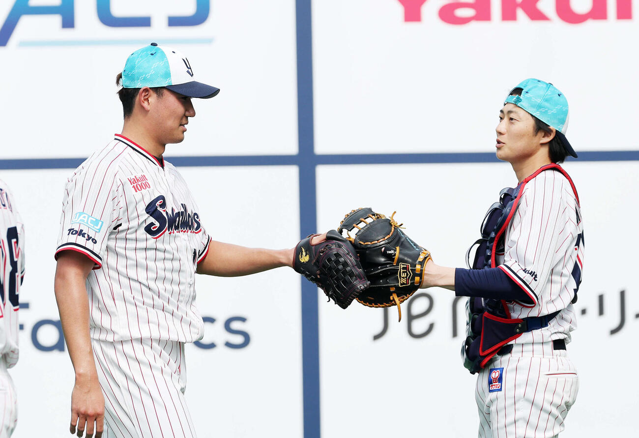 ブルペンで投球練習を終えタッチするヤクルト奥川（左）（撮影・鈴木正人）　