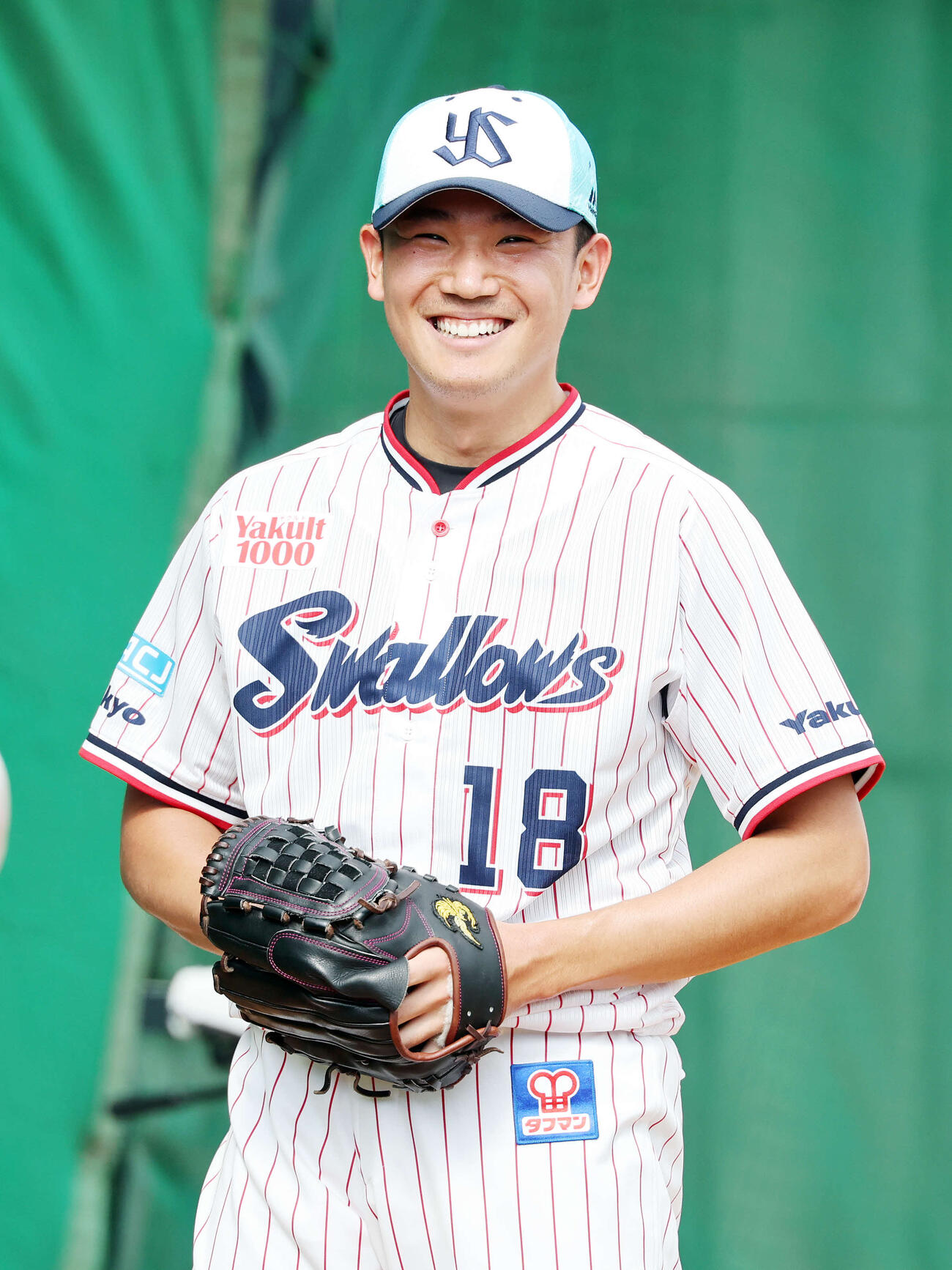 ブルペンで投球練習中、笑顔を見せるヤクルト奥川（撮影・鈴木正人）　