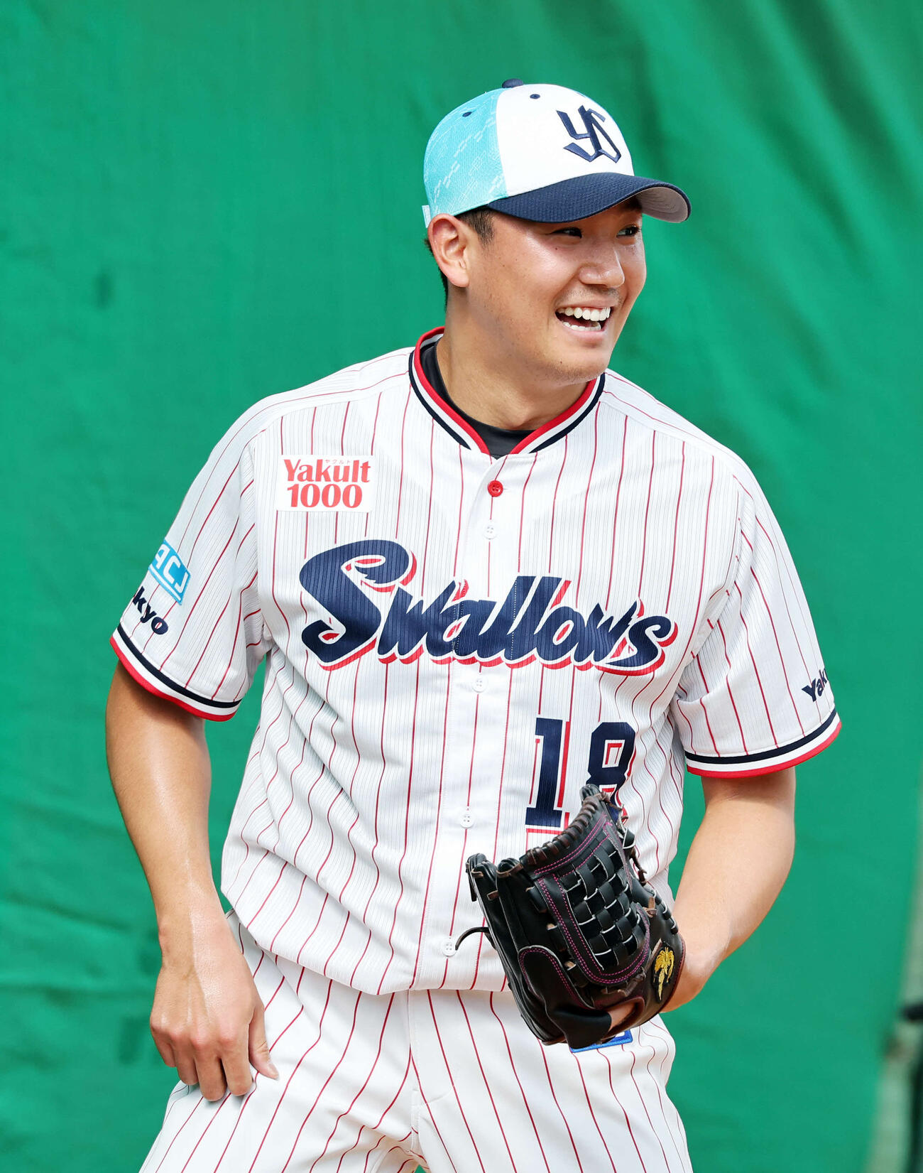 ブルペンで投球練習中、笑顔を見せるヤクルト奥川（撮影・鈴木正人）　