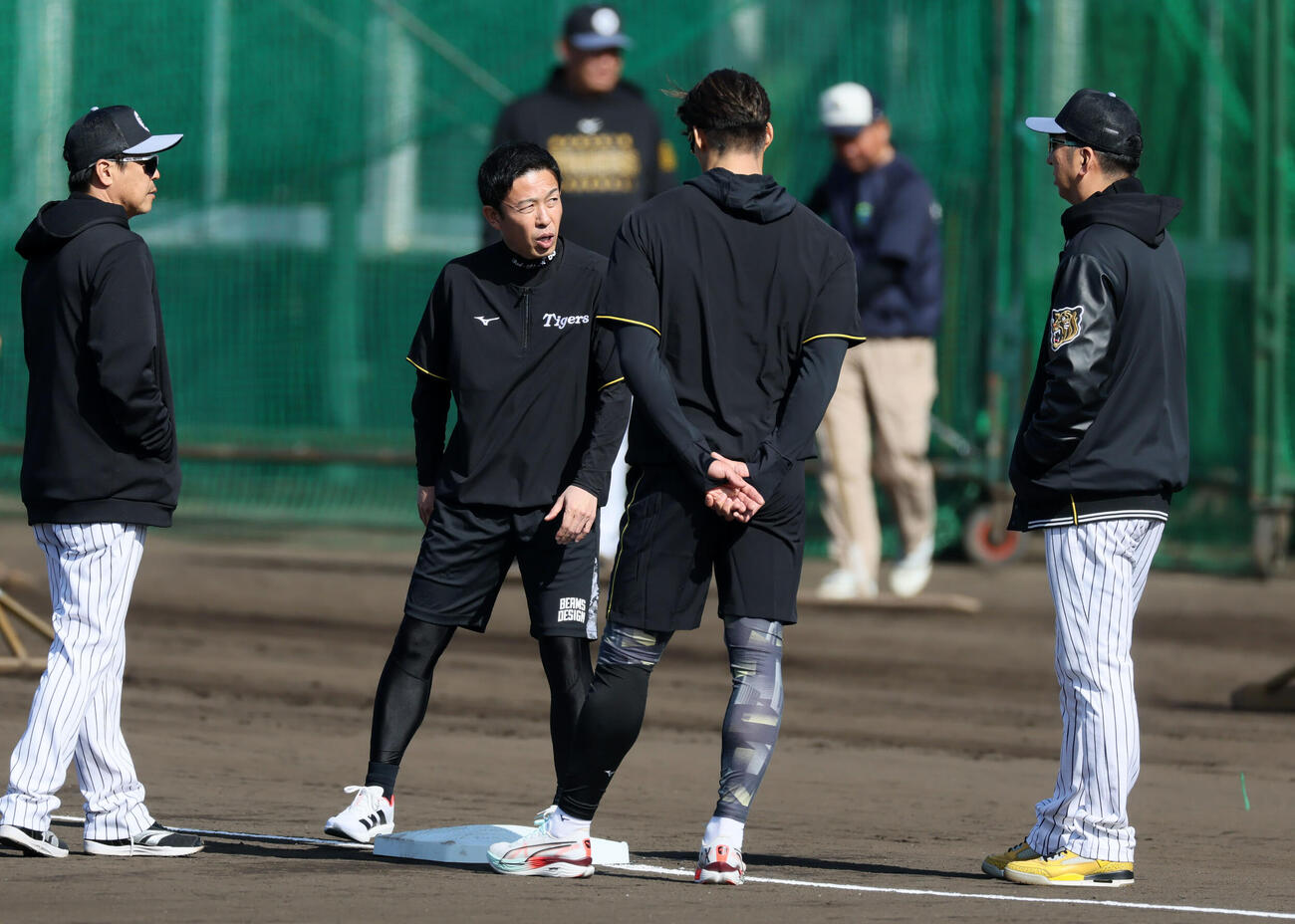 ベースを中心に話し込む左から阪神藤本コーチ、赤星臨時コーチ、糸井臨時コーチ、藤川監督（撮影・加藤哉）