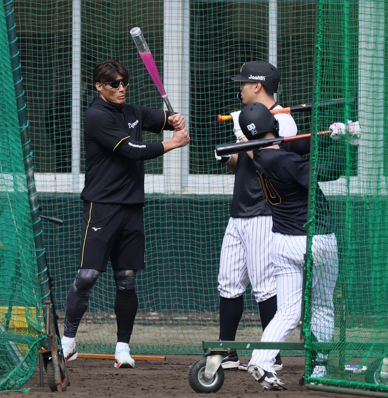 打撃練習中、アクアバットを構える糸井臨時コーチ。右は佐藤（撮影・加藤哉）