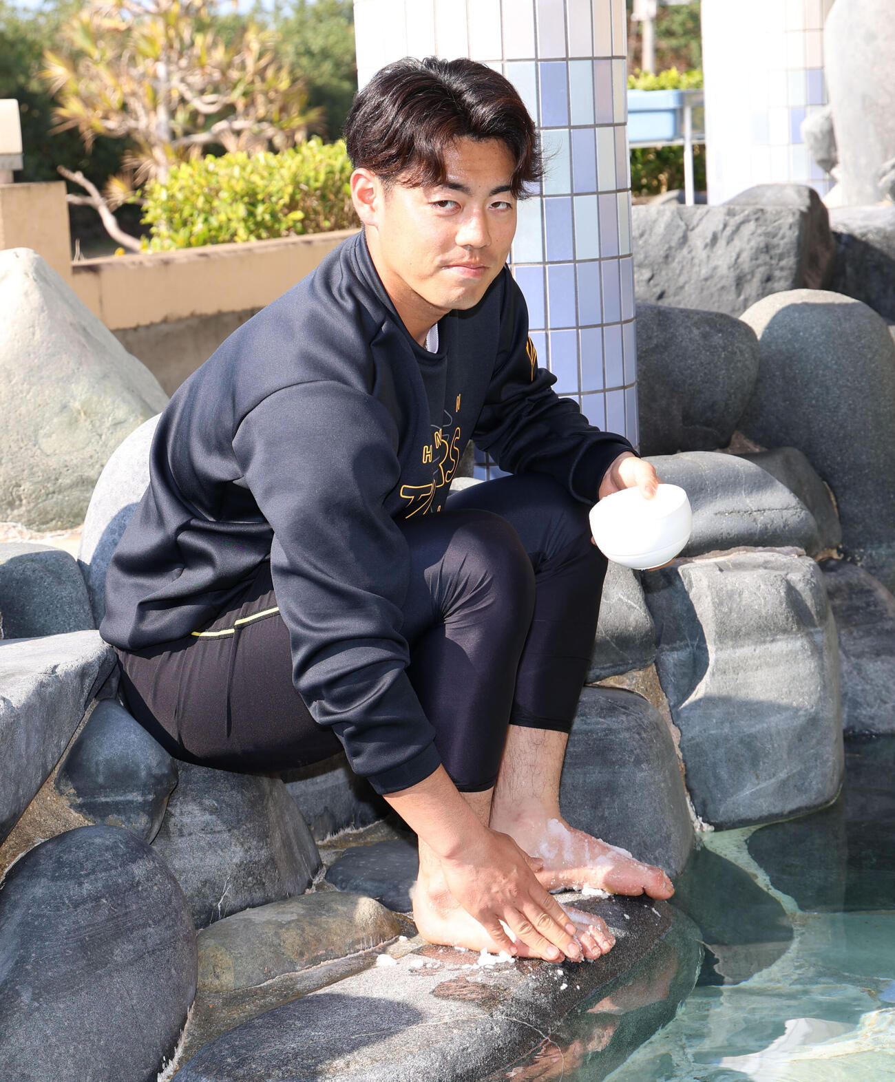 キャンプ地近くのタピックタラソセンター宜野座を訪問した阪神谷端は足湯につかったあと、足に塩を塗る（撮影・西尾就之）