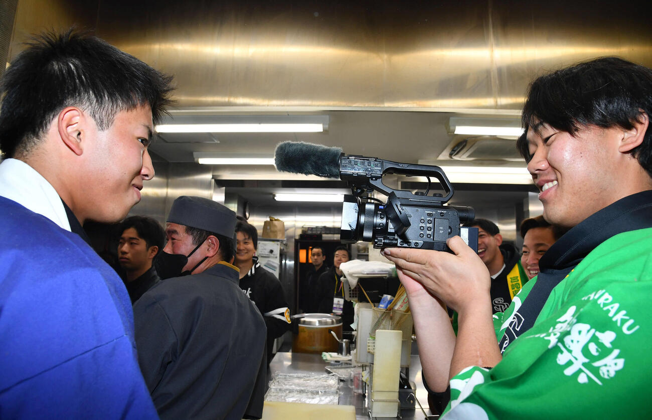 キャンプ休日、うなぎの調理中にカメラで鈴木貴（左）を撮影するソフトバンク稲川（撮影・岩下翔太）