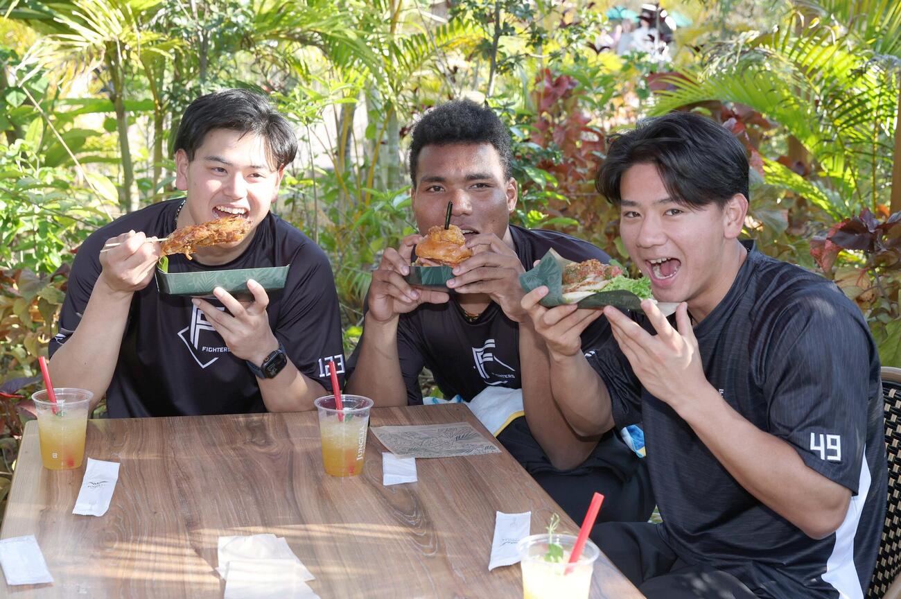 休日にジャングリア沖縄を訪れ肉にかぶりつく日本ハムの左から常谷、エドポロ、大塚（撮影・黒川智章）