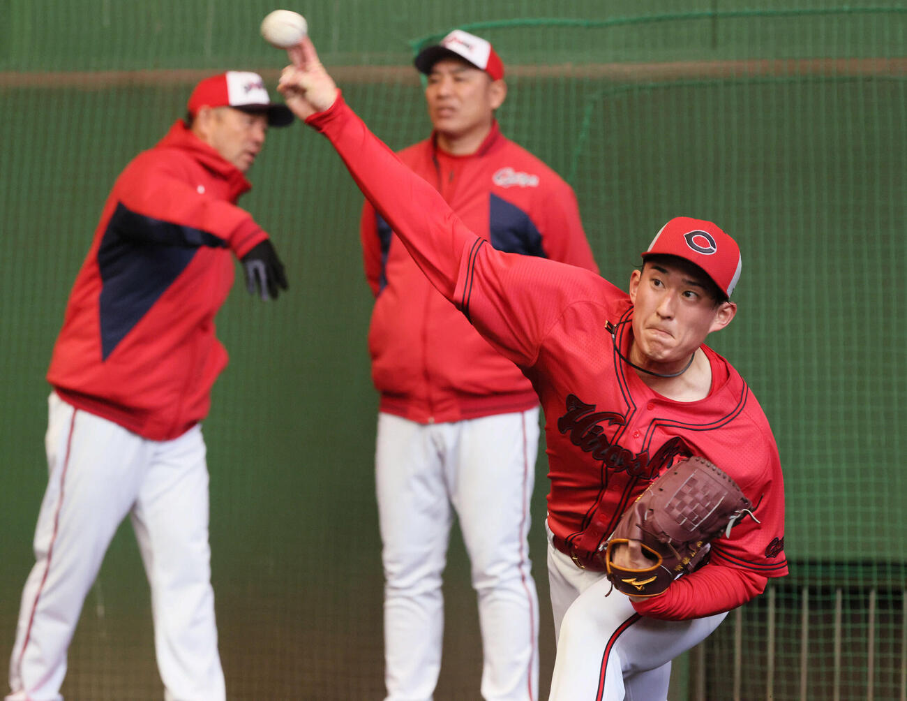 ブルペンで投げる広島ドラフト2位の斉藤汰。後ろは左から石井投手コーチ、菊地原投手コーチ（撮影・加藤孝規）
