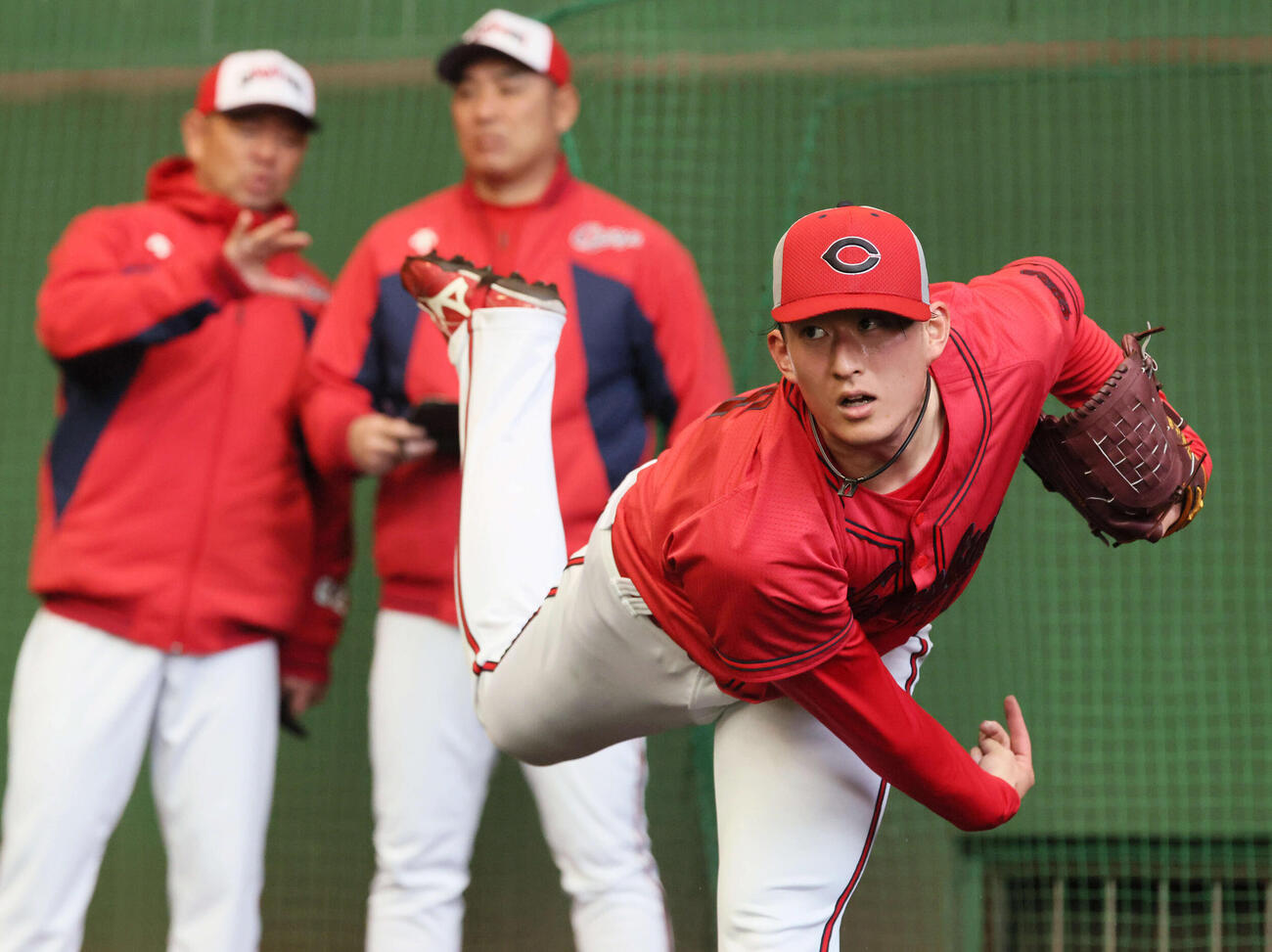 ブルペンで投げる広島ドラフト2位の斉藤汰。後ろは左から石井投手コーチ、菊地原投手コーチ（撮影・加藤孝規）