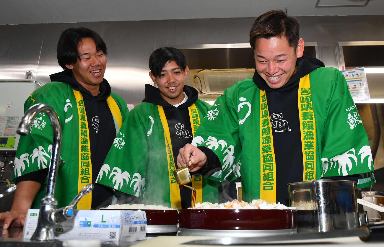 キャンプ休日、特大うな重のごはんにタレをかけるソフトバンク鈴木豪（右）を笑顔で見守る、左から稲川、大矢（撮影・岩下翔太）