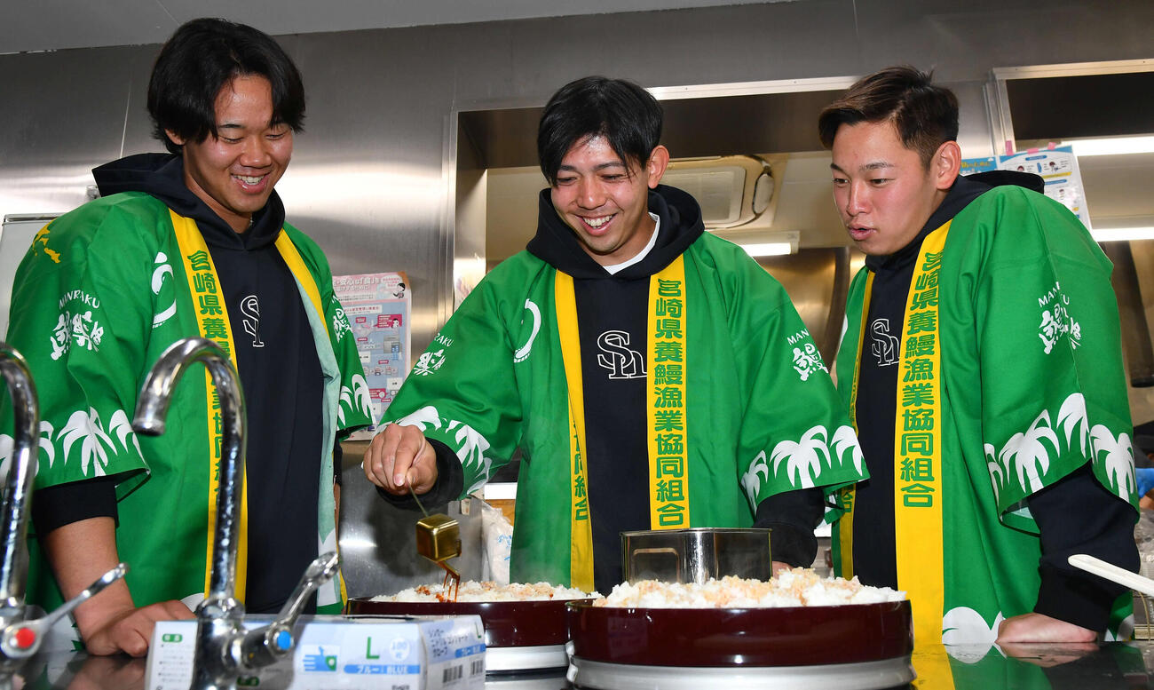 キャンプ休日、特大うな重のごはんにタレをかけるソフトバンク大矢（中央）を笑顔で見守る稲川（左）と鈴木豪（撮影・岩下翔太）