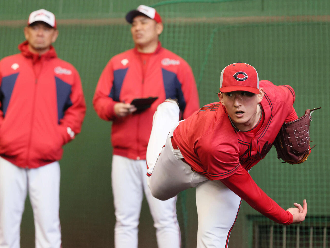 ブルペンで投げる広島ドラフト2位の斉藤汰。後ろは左から石井投手コーチ、菊地原投手コーチ（撮影・加藤孝規）