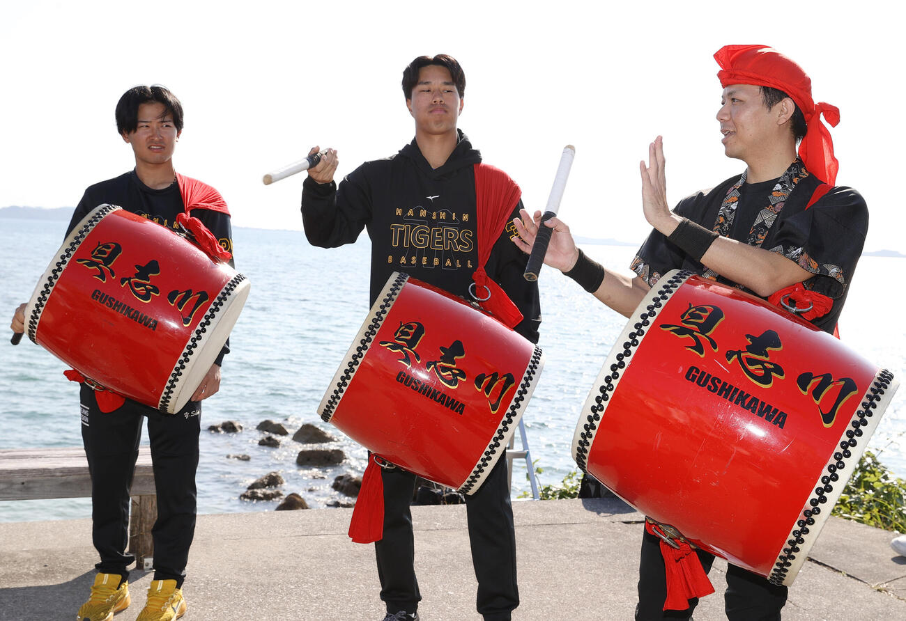 具志川ビーチでエイサー体験する阪神の岡城（中央）と山崎（左）（撮影・上山淳一）