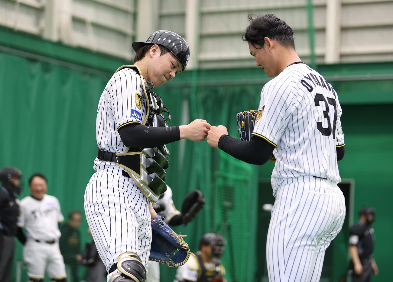 ブルペンで投球を終えた阪神及川（右）とタッチをかわす伏見（撮影・上山淳一）