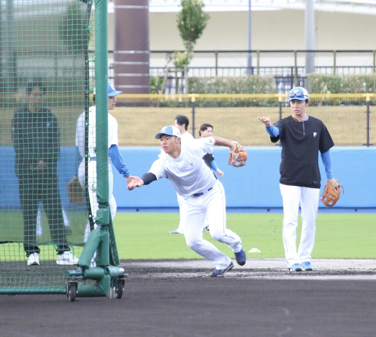 早出特守を行う日本ハム吉田、右は谷内内野守備走塁コーチ