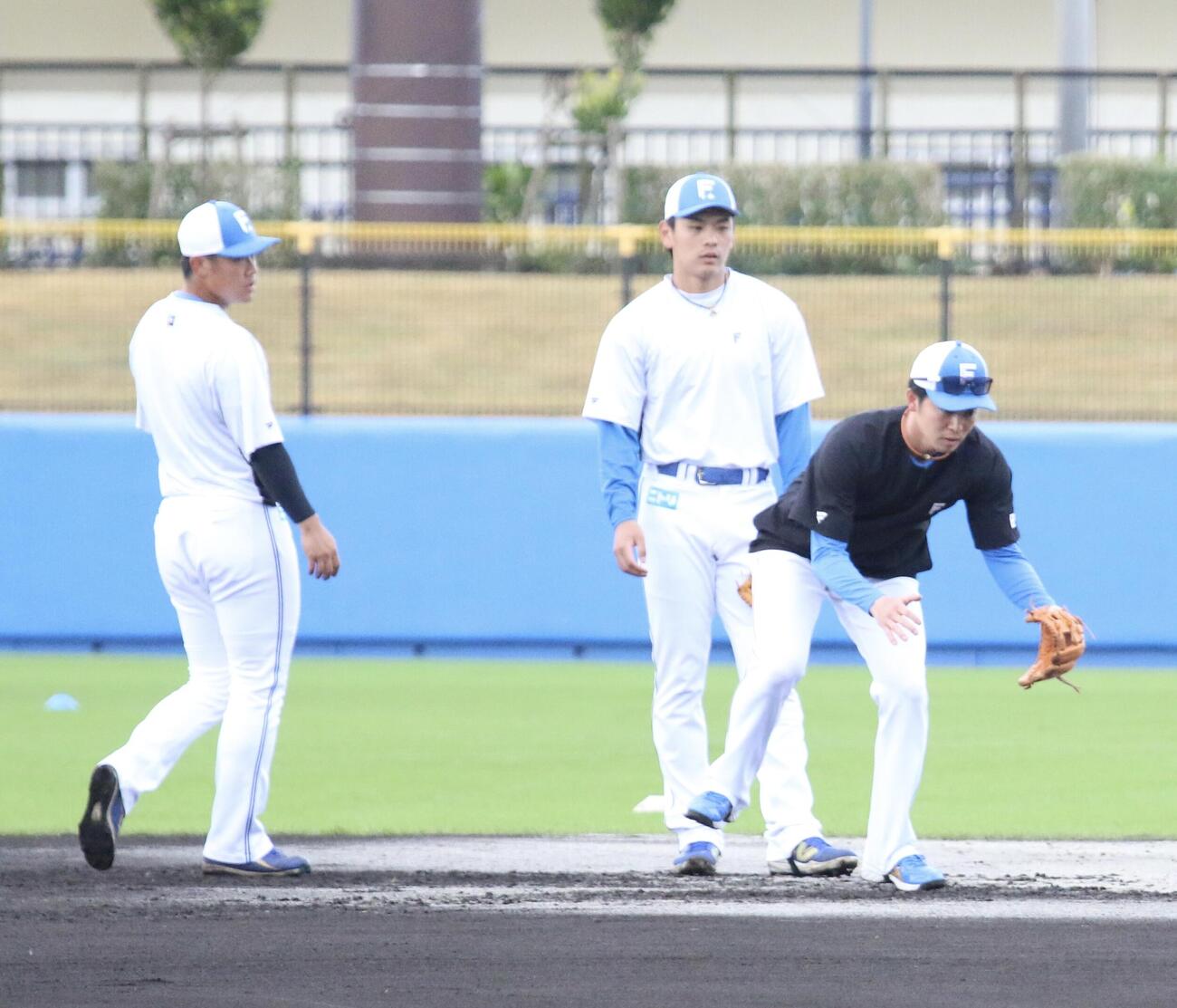 早出特守を行う日本ハム吉田（左）と野村にお手本を見せる谷内内野守備走塁コーチ（右）