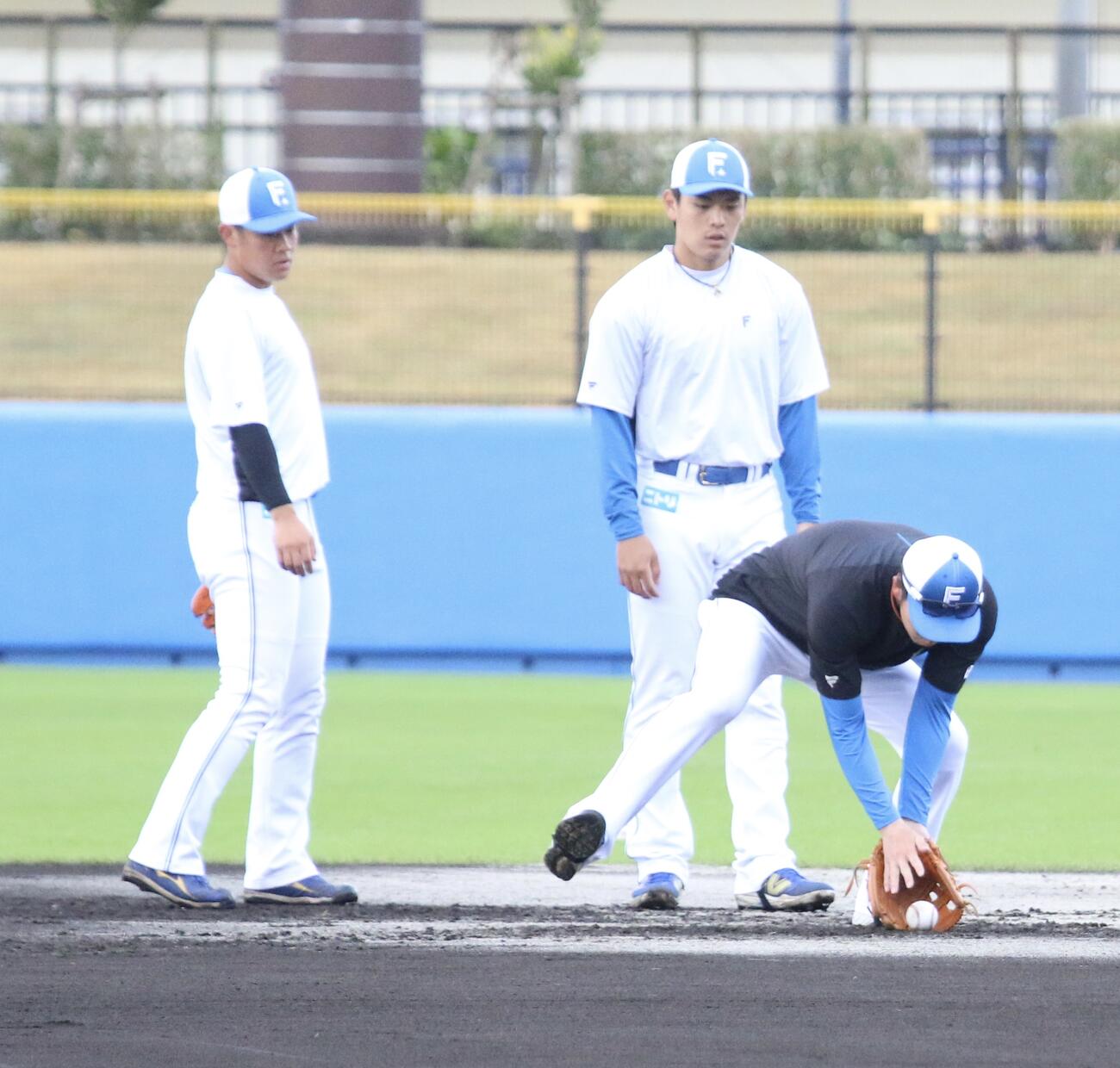 早出特守を行う日本ハム吉田（左）と野村にお手本を見せる谷内内野守備走塁コーチ（右）