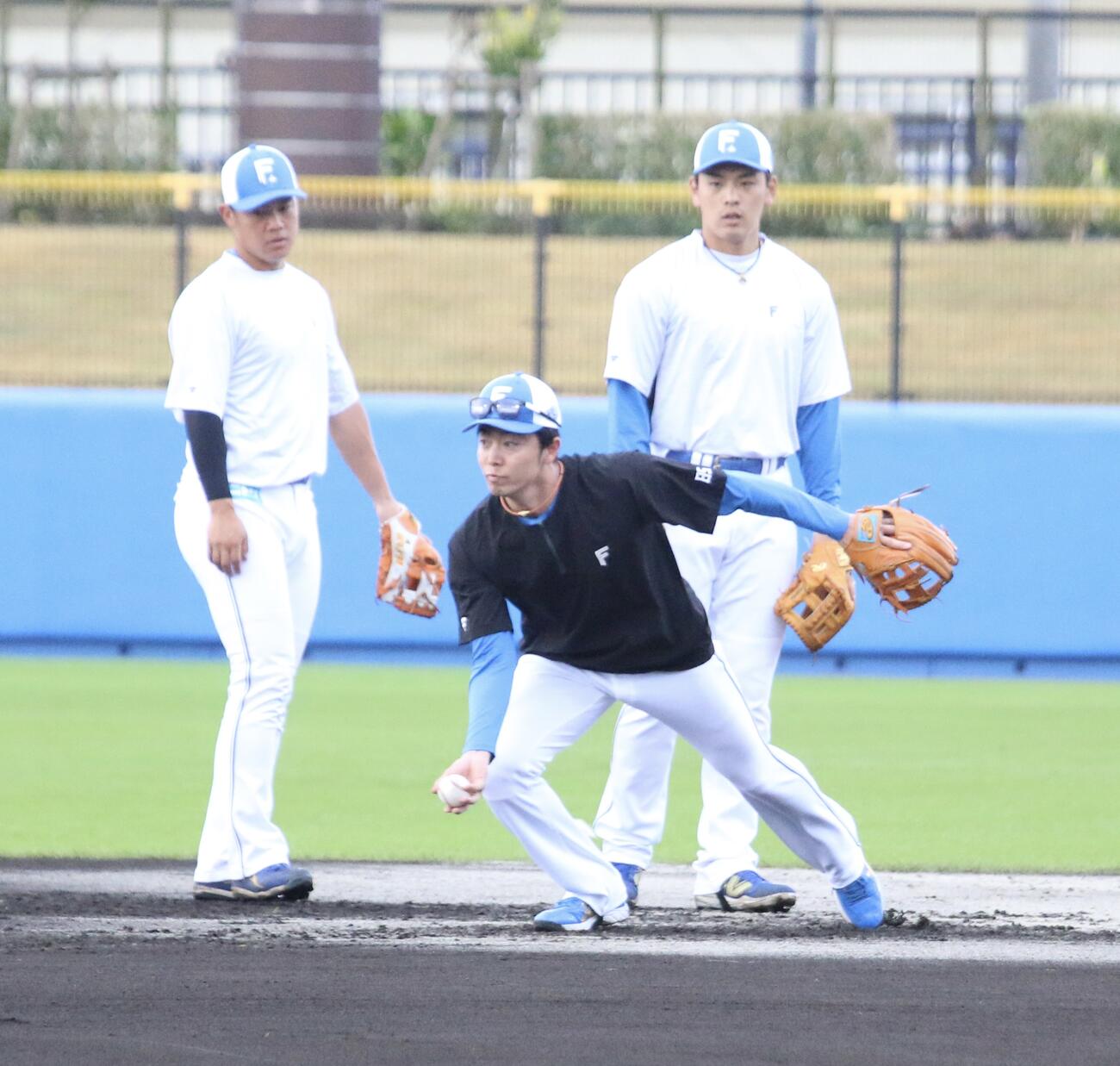 早出特守を行う日本ハム吉田（左）と野村にお手本を見せる谷内内野守備走塁コーチ（右）