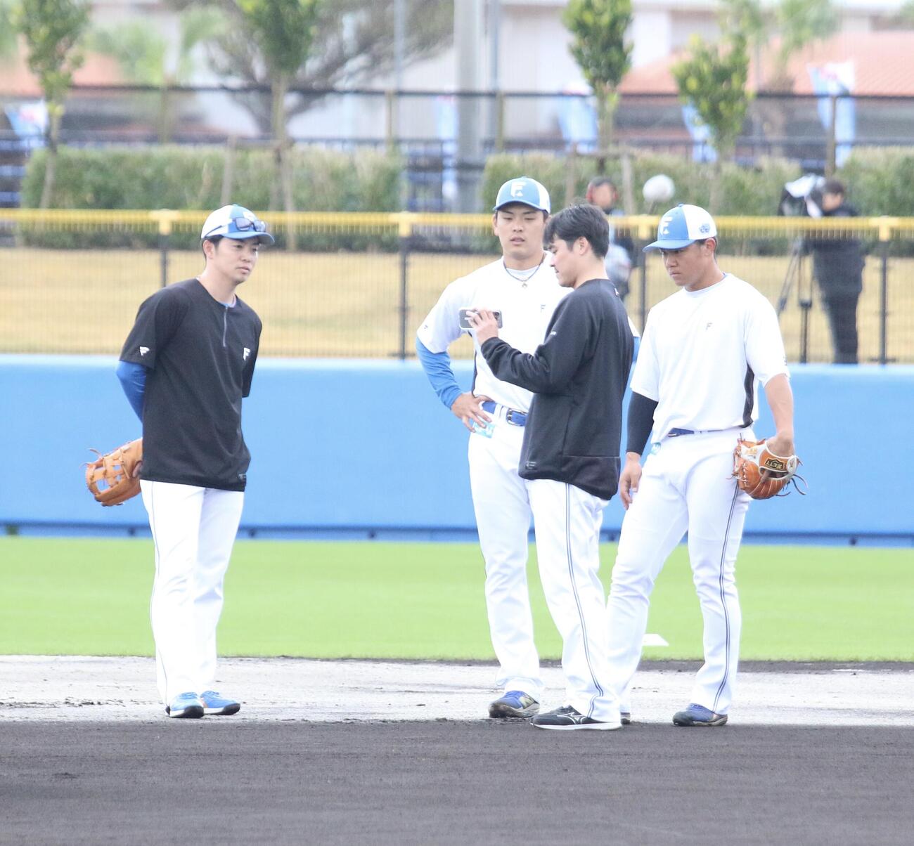 早出特守を行い、映像で動きを確認する日本ハム吉田（右）と野村、それを見守る谷内内野守備走塁コーチ（左）＝2026年2月7日