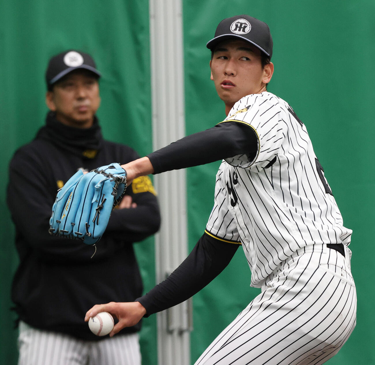 ブルペンで投球する阪神今朝丸。奥は阪神藤川監督（撮影・上山淳一）