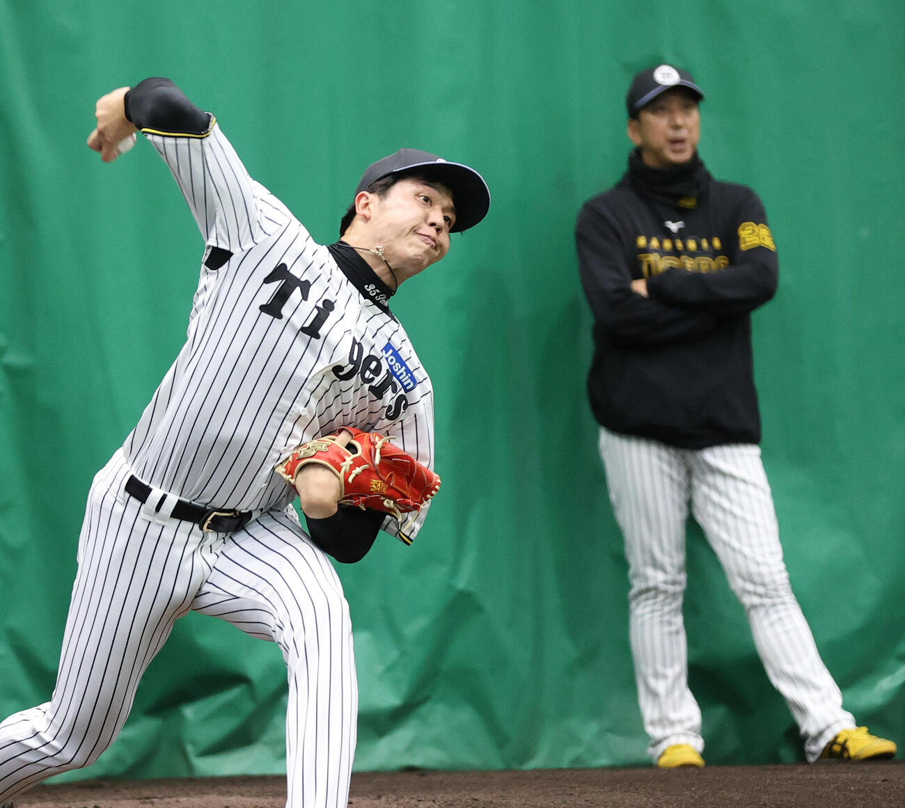 阪神才木（手前）は藤川監督が見守る中、ブルペンで投げこむ（撮影・上山淳一）