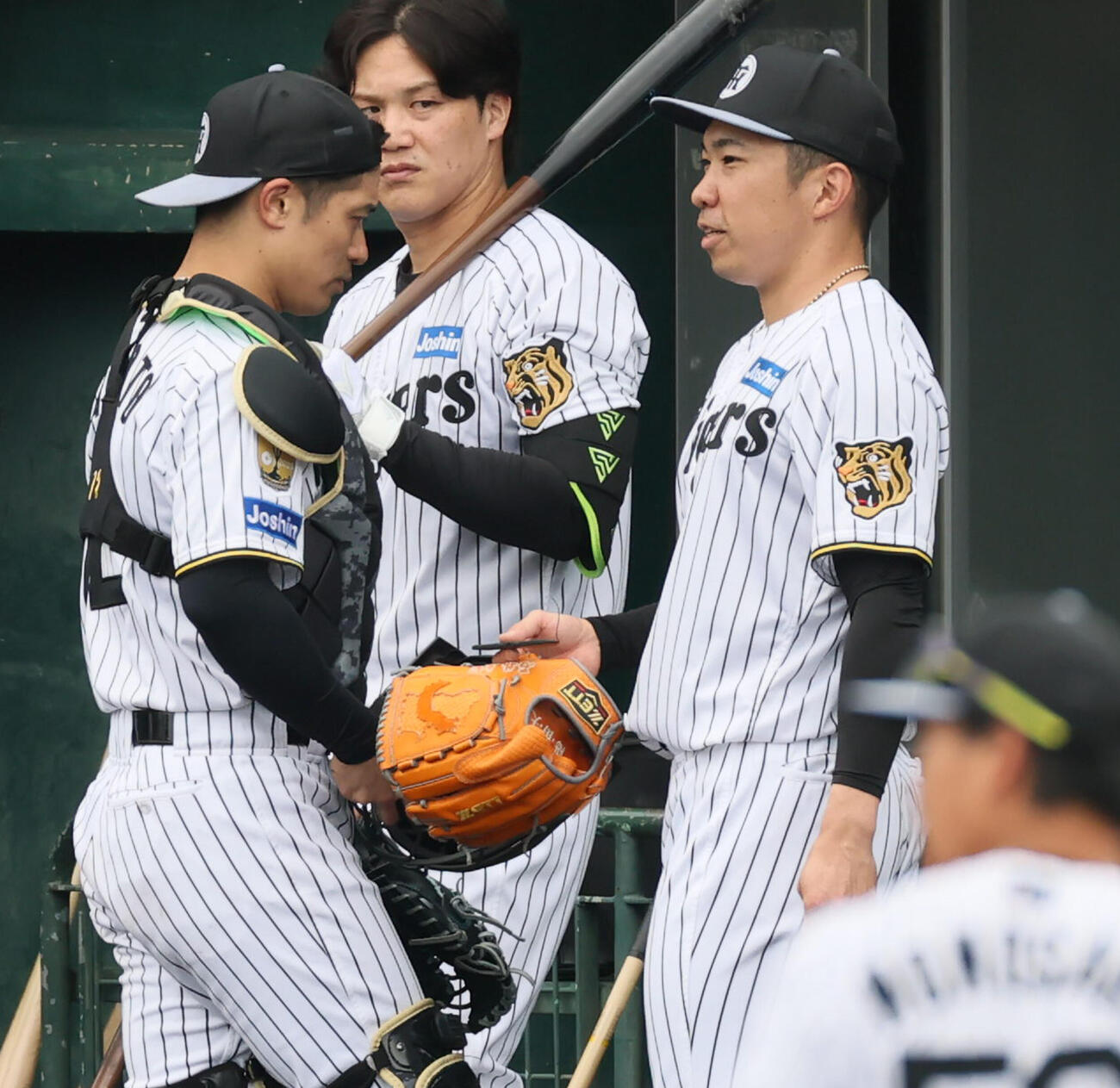 シート打撃練習で装着していたピッチコムの機械を右手で持つ阪神石井。左は坂本（撮影・加藤哉）