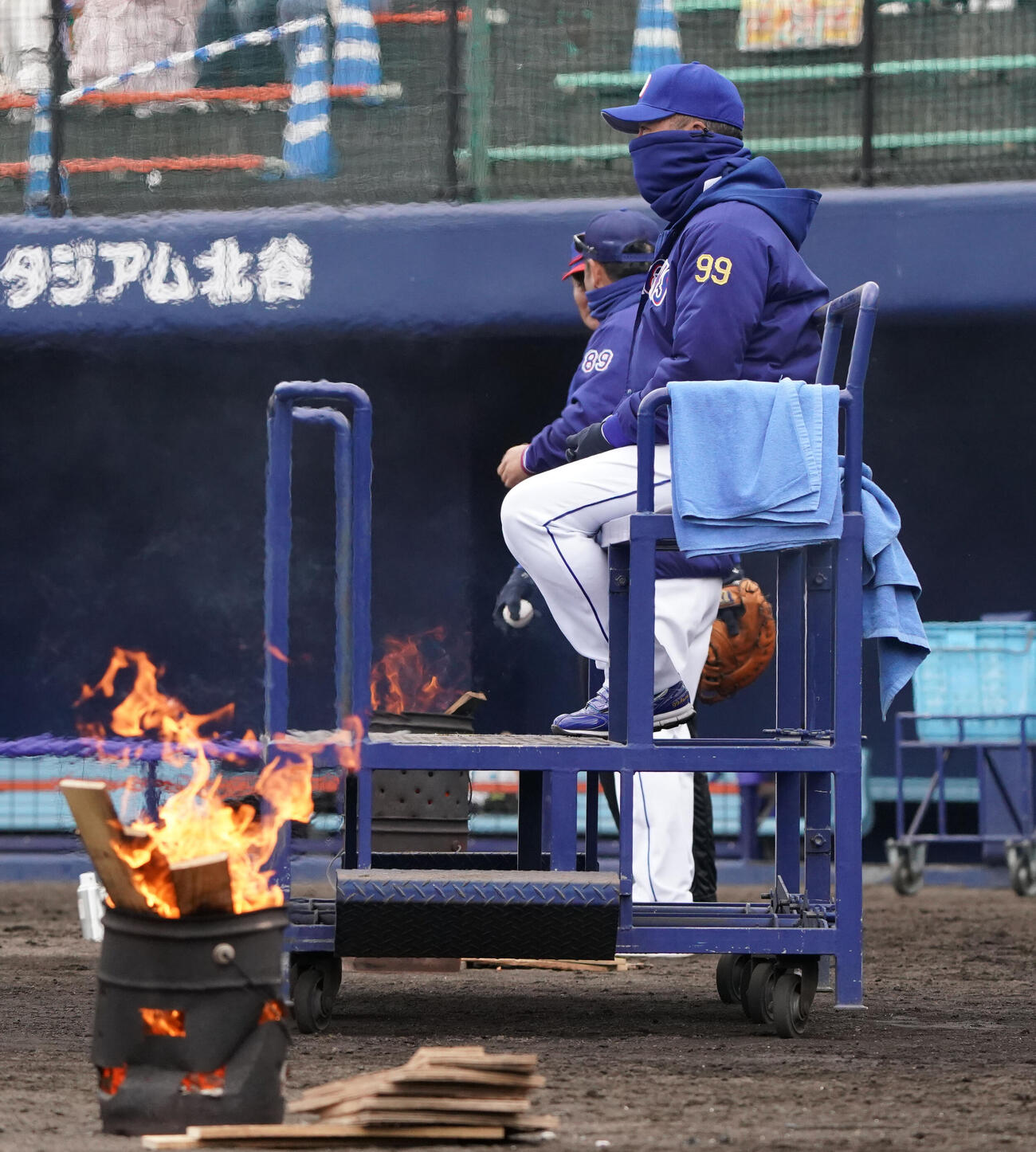 練習を見つめる井上監督のそばにはたき火が置かれる（撮影・森本幸一）