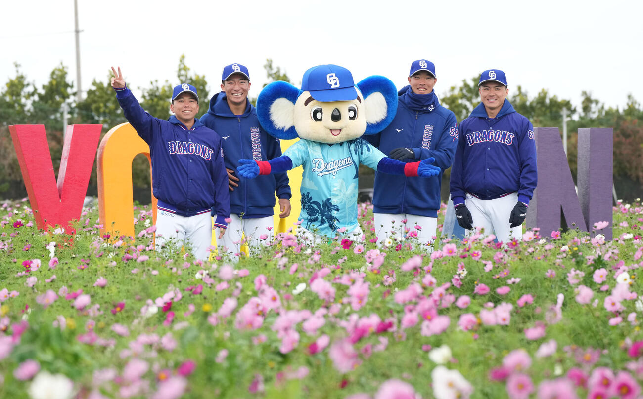練習終了後、恒例のいちゃびら祭に参加しコスモス畑で記念撮影に納まる（左から）三上、石川大、ドアラ、篠崎、能戸（撮影・森本幸一）