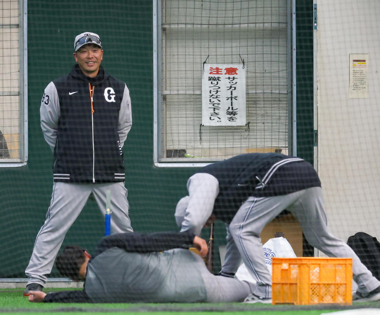 股割りノックを終えストレッチする巨人石塚（手前左）を見て笑う阿部監督（撮影・増田悦実）