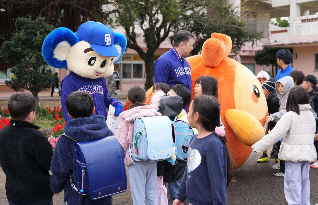 キャンプ地の小学校を訪れあいさつ運動を行う奥・左からドアラ、北谷町の渡久地町長、ちーたん（撮影・森本幸一）
