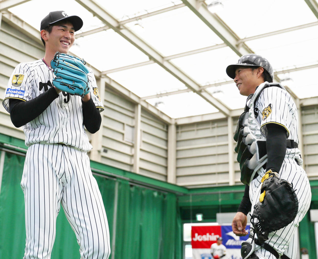 ブルペンで投球を終えた阪神今朝丸（左）は藤田と笑顔で話す（撮影・上山淳一）