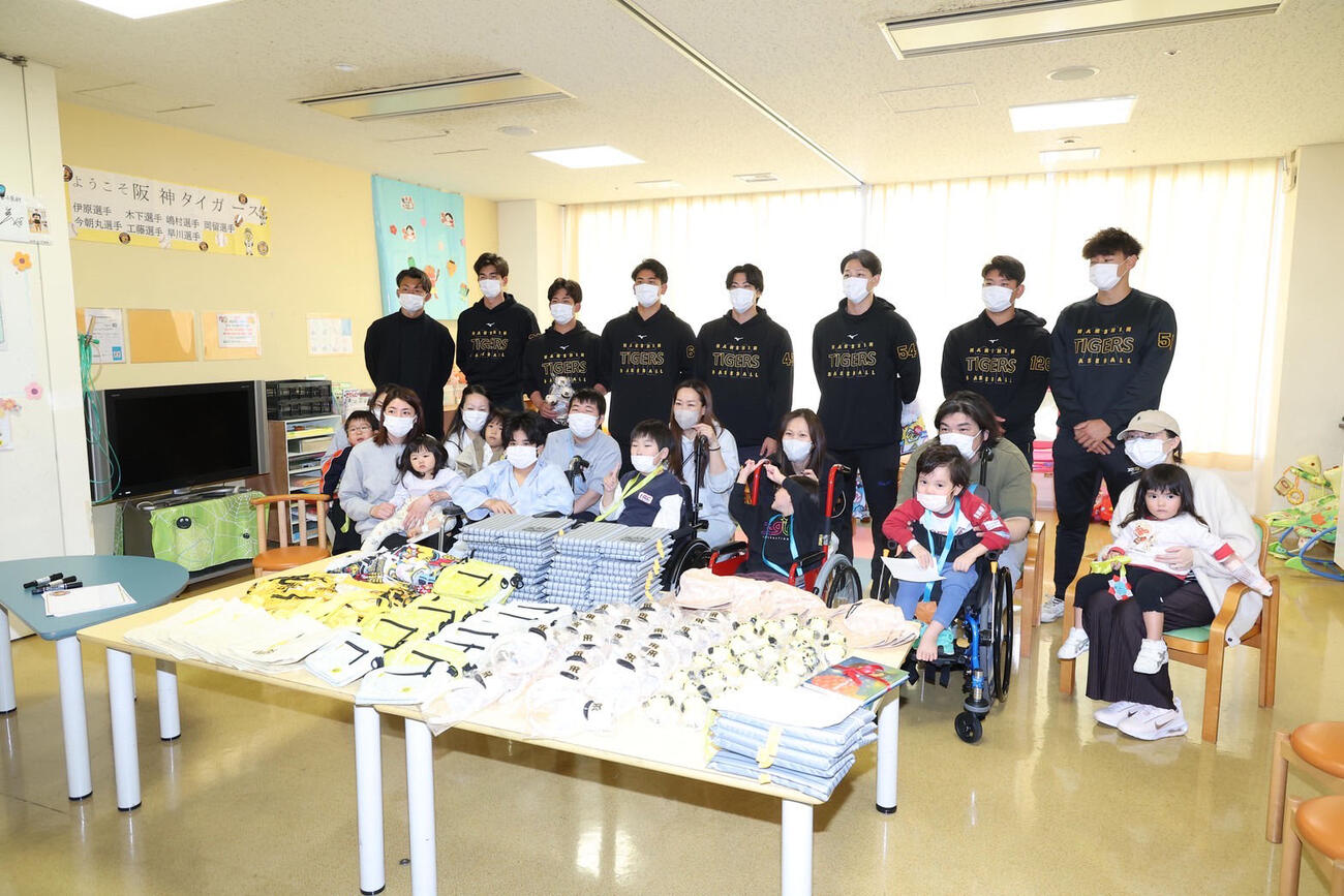 病院を訪問し、患者と家族と記念写真に納まる、後列左から阪神OBの鳥谷敬氏、今朝丸、伊原、岡留、工藤、木下、嶋村、早川