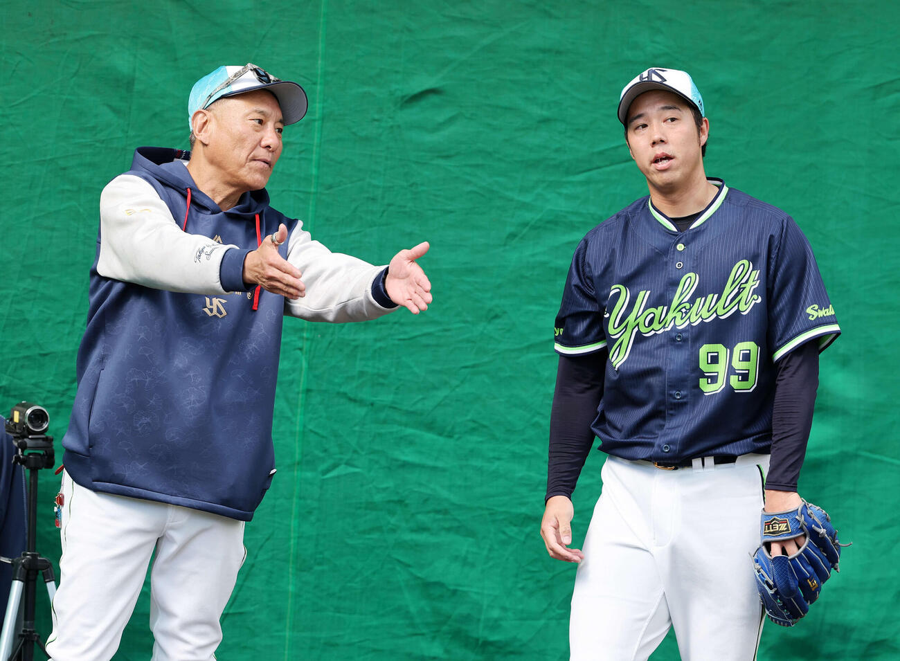 ブルペンで投球練習中、会話するヤクルト池山監督（左）と青柳（撮影・鈴木正人）　