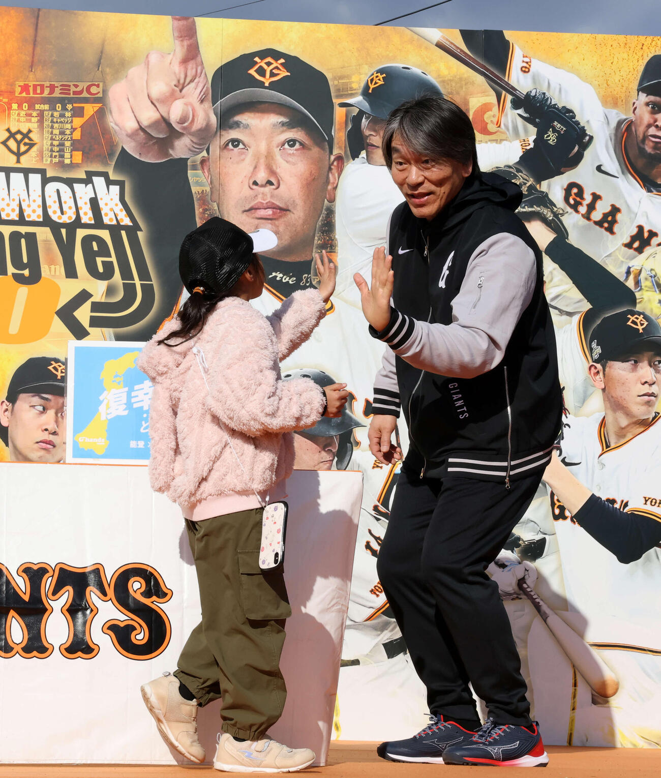練習後、能登復興募金を募り、ファンとハイタッチする巨人松井臨時コーチ（撮影・浅見桂子）