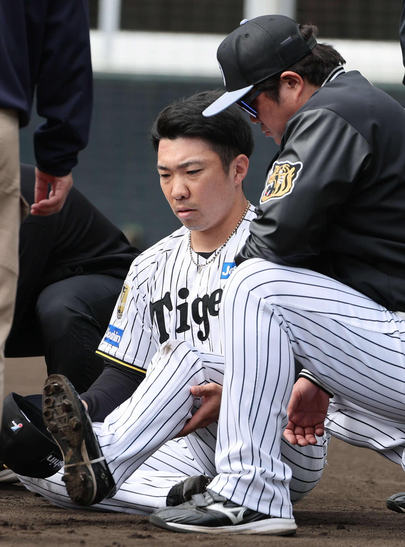 グラウンドにしゃがみ込み、左足を気にするそぶりを見せる石井大智（26年2月11日撮影）