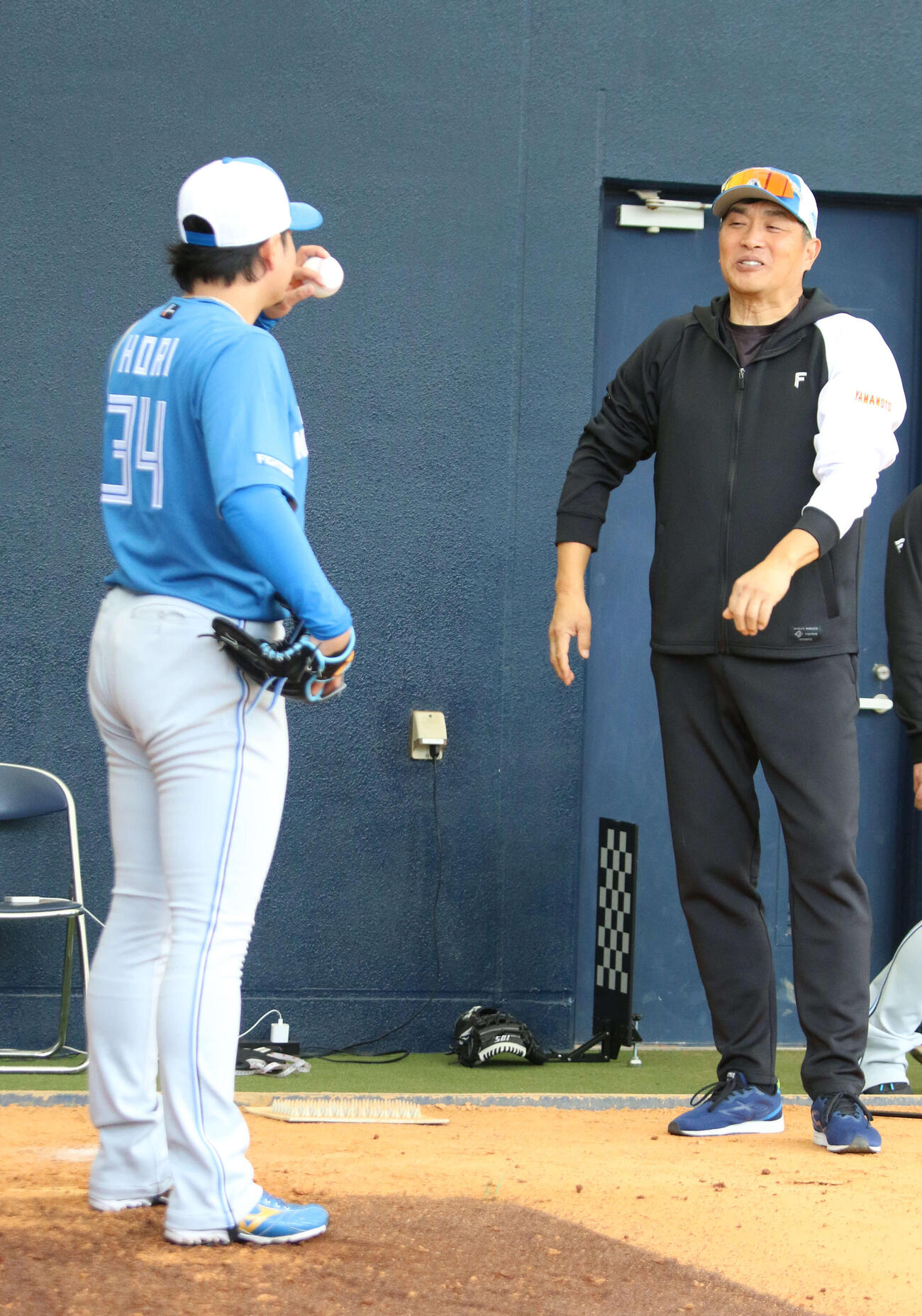 ブルペン入りした日本ハム堀（左）に指導する山本昌臨時コーチ（撮影・木下大輔）