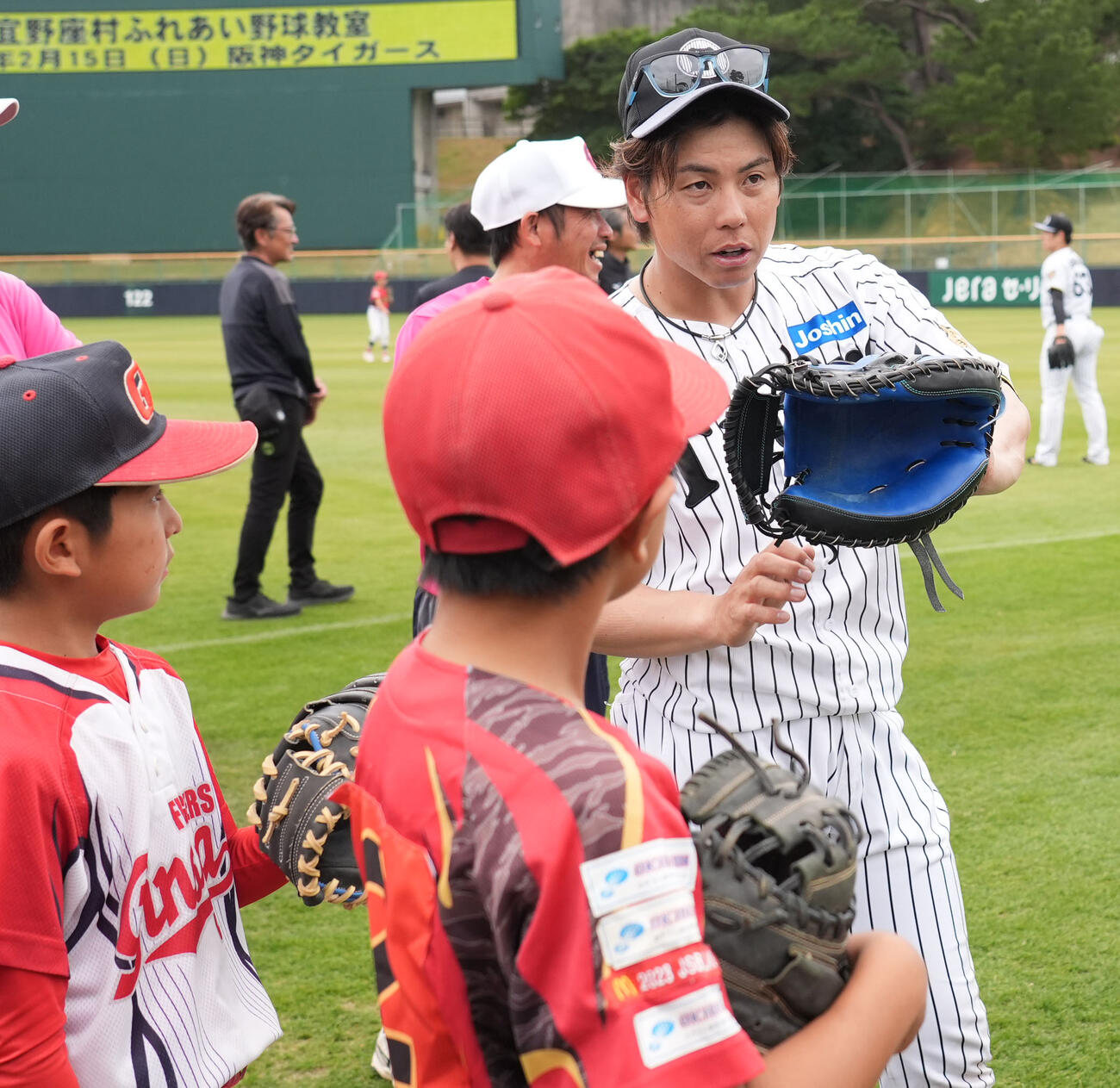 梅野（右）は練習後に行われた野球教室で子どもたちにアドバイスをする（撮影・森本幸一）