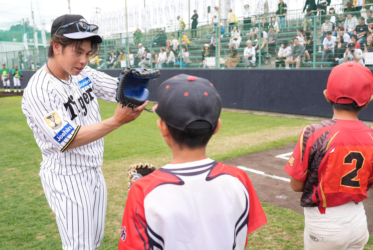 梅野（左）は練習後に行われた野球教室で子どもたちにアドバイスをする（撮影・森本幸一）