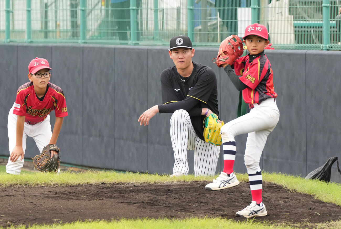 及川（中央）は練習後に行われた野球教室で子どもたちにアドバイスをする（撮影・森本幸一）