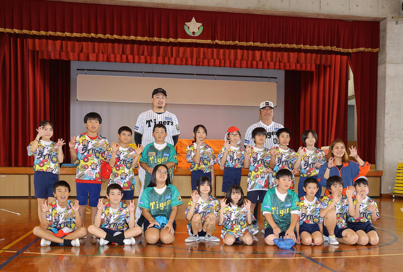 ゲストティーチャーで訪れた松田小学校で児童らと記念撮影をする阪神秋山BA（中央左）とOBの亀山氏（撮影・上田博志）