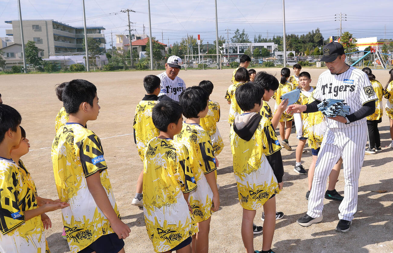 児童にプレゼントを手渡す阪神秋山拓巳BA（右）とOBの亀山努氏（撮影・上田博志）