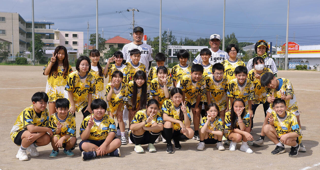 ゲストティーチャーで訪れた宮森小学校で児童と記念撮影をする阪神秋山BA（左）とOBの亀山氏（撮影・上田博志）
