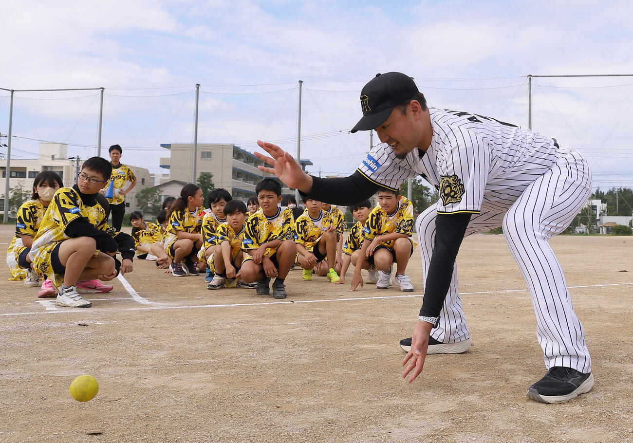 ゲストティーチャーで訪れた宮森小学校で児童にボールの捕り方を教える阪神秋山BA（撮影・上田博志）