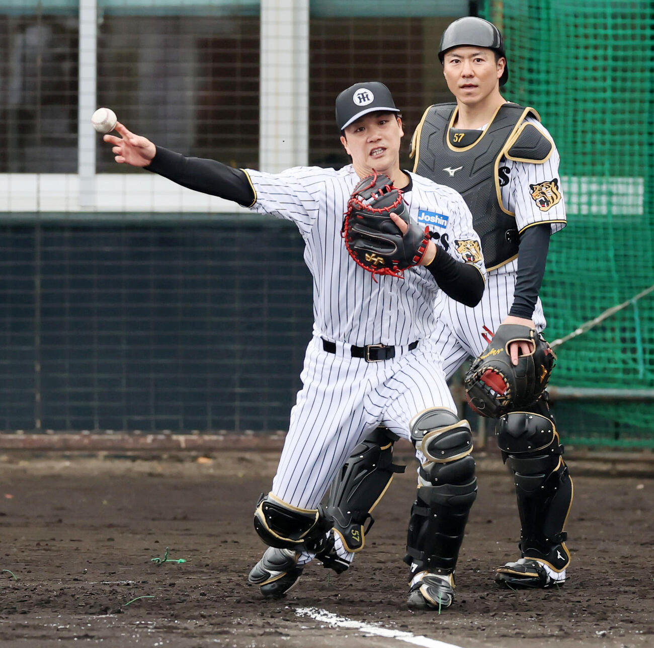 9日、シートノックで三塁へ送球する阪神伏見。右は長坂
